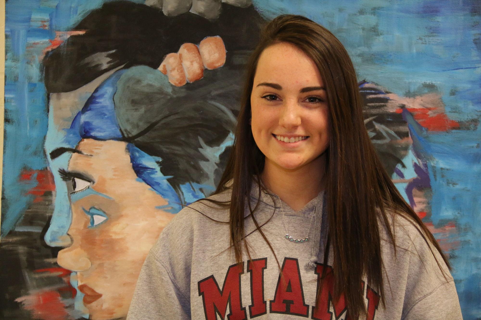 Julia Kuhr standing in front of her painting titled, "Double Vision."