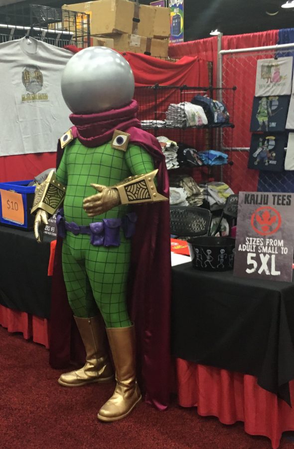 A cosplayer stands in front of a booth.