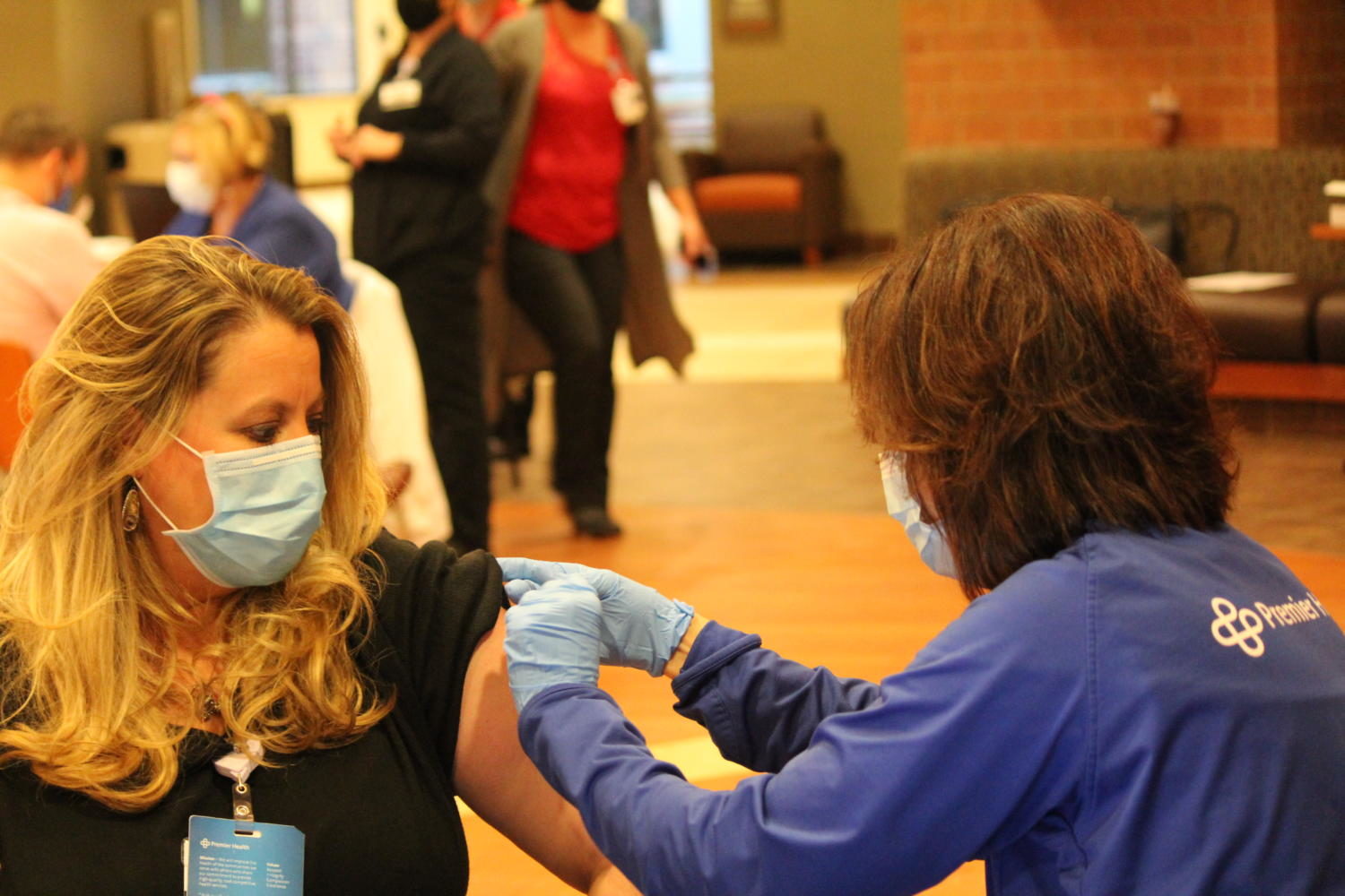 Physician at Hiltop OBGYN Heather Hilkowitz (left) is administered her first dose of the Moderna vaccine by Chief Nursing and Operating Officer at Atrium Medical Center Marquita Turner (right). 
