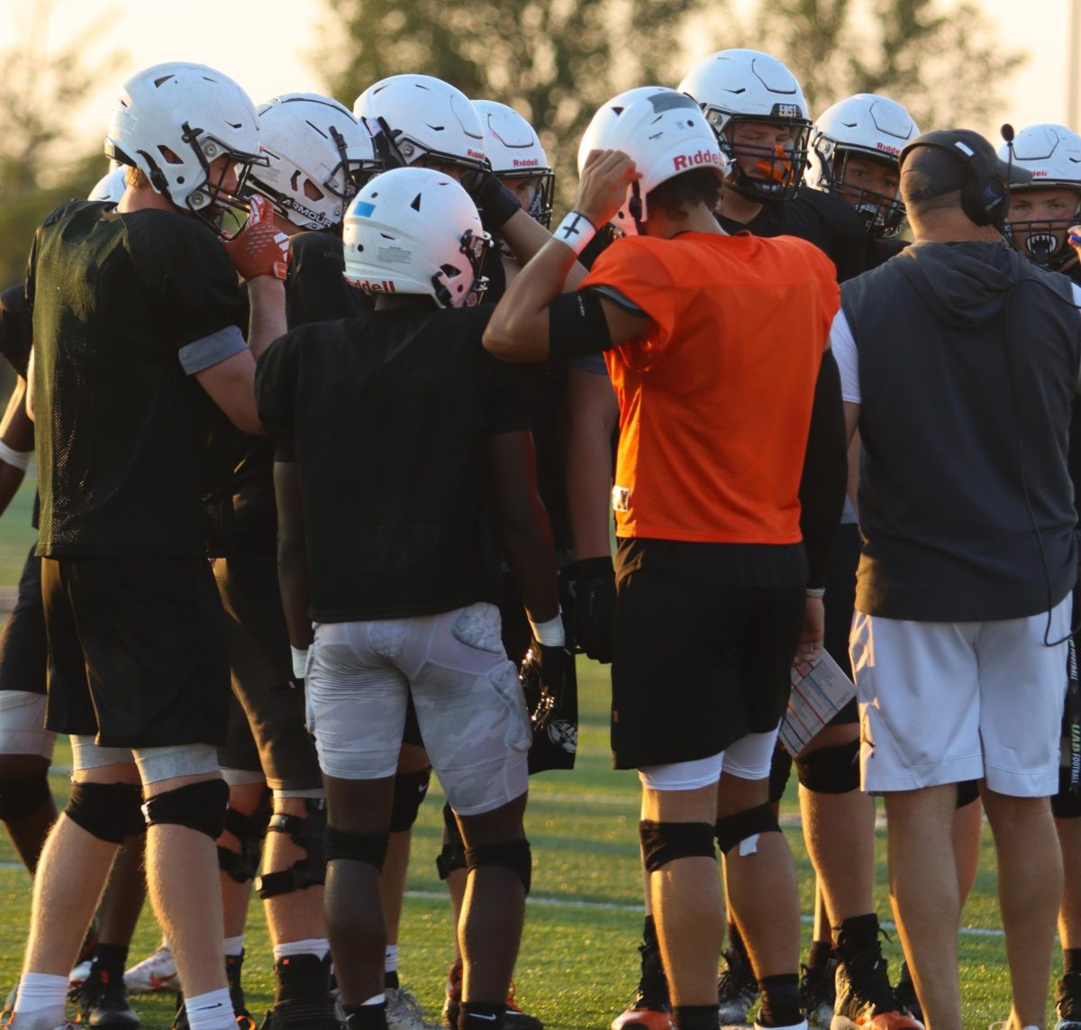 The offensive line huddles before a play, led my quarterback Jamison (JT) Kitna. East Varsity Football plays a scrimmage against La Salle High School on Aug. 9, ending in a 12-7 loss from the Thundhawks.