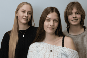 From left to right, the sisters stand in order of youngest to oldest. Standing in the middle, Caitlyn portrays her role as the medium between her sisters.