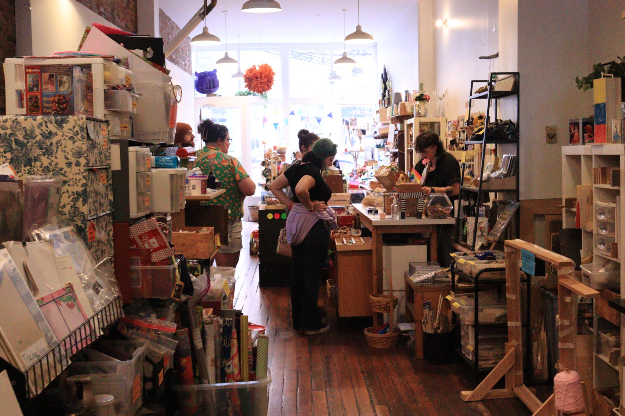 Customers wait in line while Moscoe checks them out. Others browse through the store, sifting through the many available art supplies.